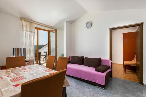 a living room with a purple couch and a table at Apartments Pino Rabac in Rabac