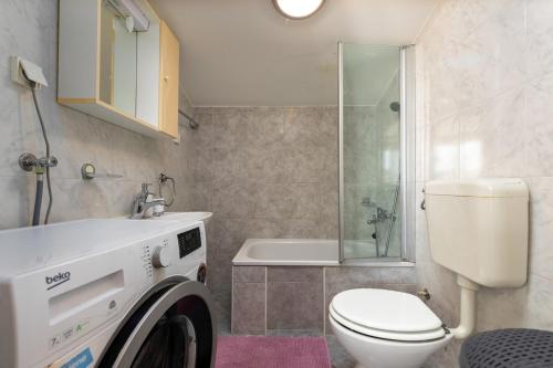 a bathroom with a toilet and a washing machine at Apartments Pino Rabac in Rabac
