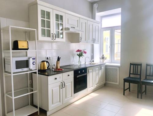 a white kitchen with white cabinets and a microwave at O'Key Home in Rostov on Don