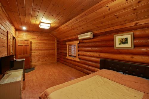 1 dormitorio con 1 cama en una cabaña de madera en Muju Log House Pension, en Muju