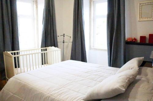 a white bed with pillows in a bedroom with windows at Casa do Adro- Douro in Peso da Régua