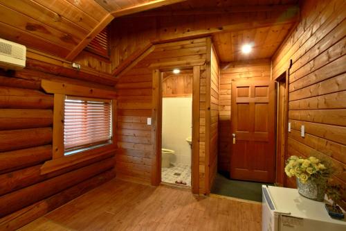 Cabaña de madera con baño con aseo y puerta en Muju Log House Pension, en Muju