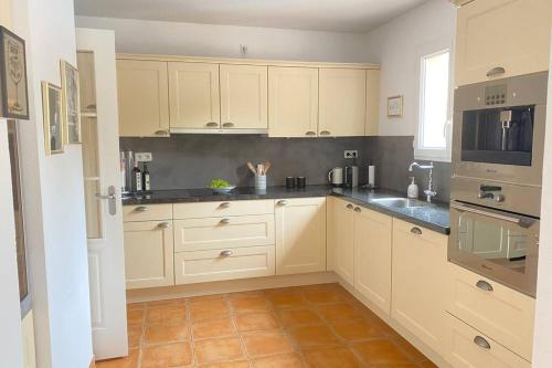 a kitchen with white cabinets and a tile floor at Château de Charme in Vallon-Pont-dʼArc