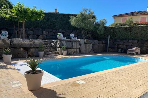 a swimming pool in a yard with a stone wall at Château de Charme in Vallon-Pont-dʼArc