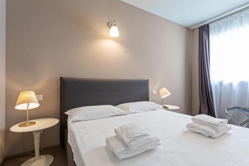 a bedroom with a white bed with towels on it at JOIVY Treviso Vittoria in Treviso