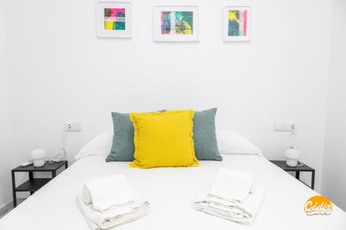 uma cama branca com uma almofada amarela em Casa Patio La Viña by Cadiz Time em Cádiz