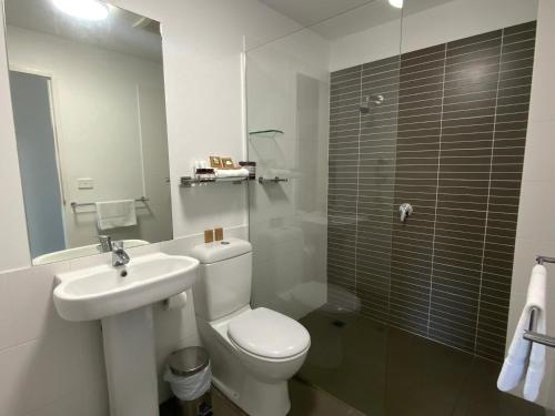 
a bathroom with a toilet a sink and a shower at Honeysuckle Executive Apartments in Newcastle
