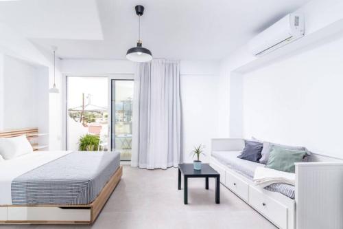 Maisonnette Giannis في بيتسيديا: غرفة نوم بيضاء مع سرير وأريكة
