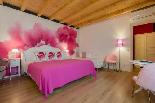 a bedroom with a pink bed and a painting on the wall at Giardino Giusti House & Court in Verona