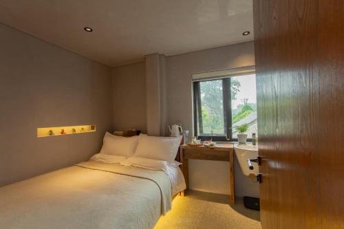 a bedroom with a bed and a desk and a window at 北京重构空间酒店天安门王府井店 in Beijing