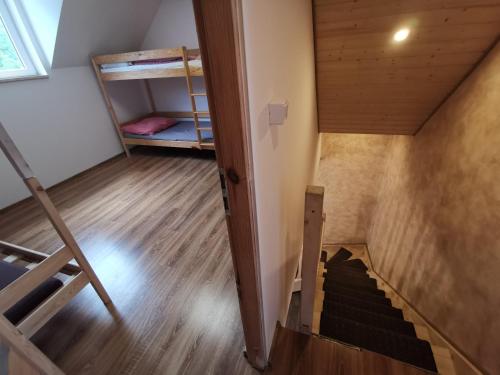 an attic room with a staircase and bunk beds at Schronisko młodzieżowe w Jabłonkach in Jabłonki