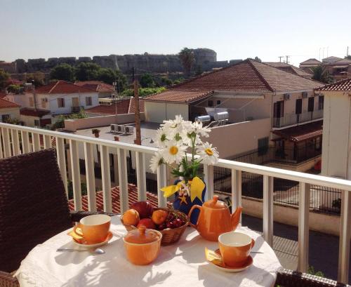 a table with a bowl of fruit and flowers on a balcony at Hotel Alex in Methoni