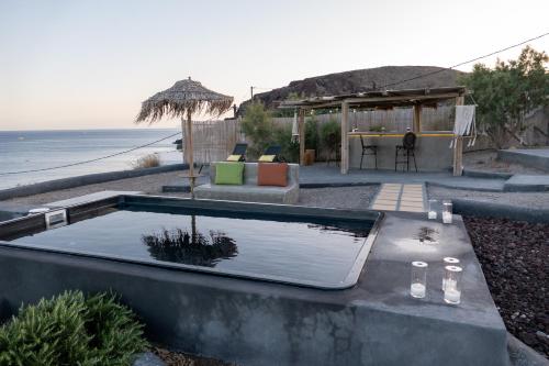 a swimming pool next to the ocean with a table at Le Grand Blue Villa in Akrotiri