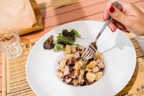 a person eating a plate of food with a fork at Golfo del Sole Hotel & Holiday Resort in Follonica
