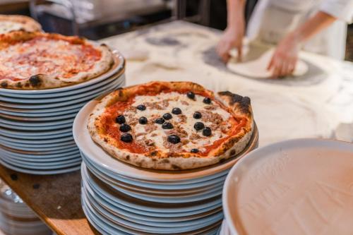 two pizzas sitting on stacks of plates on a table at Golfo del Sole Hotel & Holiday Resort in Follonica