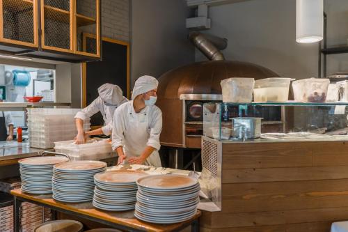 two chefs standing in a kitchen preparing food at Golfo del Sole Hotel & Holiday Resort in Follonica