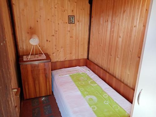 a small bed in a wooden room with a lamp at Vikendica Ovčar Banja in Čačak