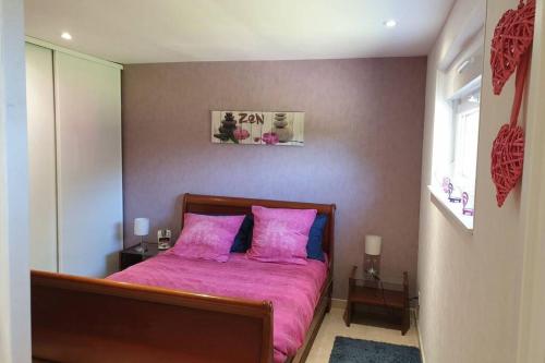 a bedroom with a pink bed with two pink pillows at Agréable logement pour 4 pers à deux pas de Verdun in Haudainville