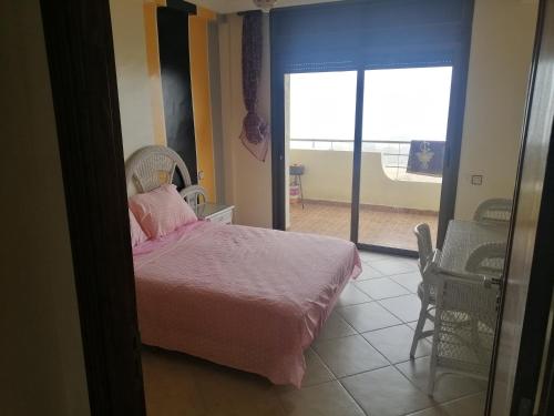 Schlafzimmer mit einem Bett mit rosa Bettwäsche und einem Fenster in der Unterkunft Akwass Marina Assilah in Asilah