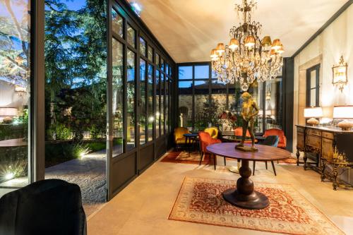 a living room with a chandelier and a table at Hôtel Villa Alexandre in Régnié