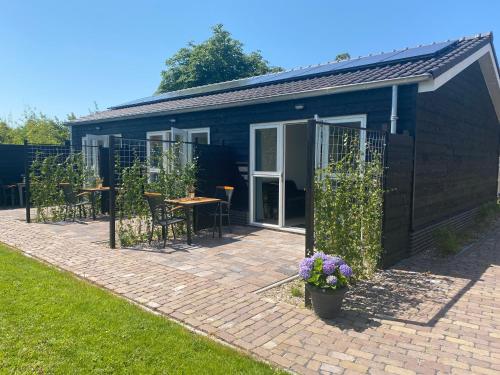 a black building with a patio with a table and chairs at Studio Duinroos in Burgh Haamstede