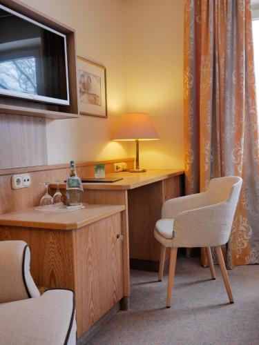 a bathroom with a sink and a desk with a lamp at Landhotel Bauernwald in Faßberg