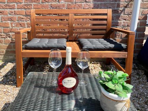 una botella de vino sentada en una mesa con dos copas de vino en Lise's Place en Vrouwenpolder