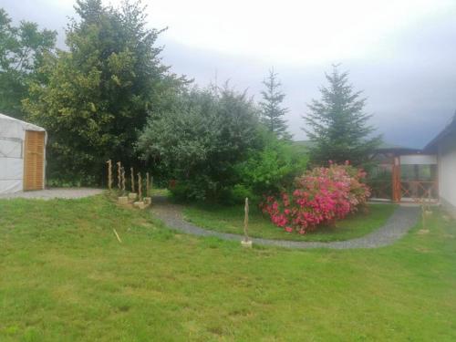 a garden with trees and pink flowers and a building at Jurta Hotel Balatongyörök in Balatongyörök