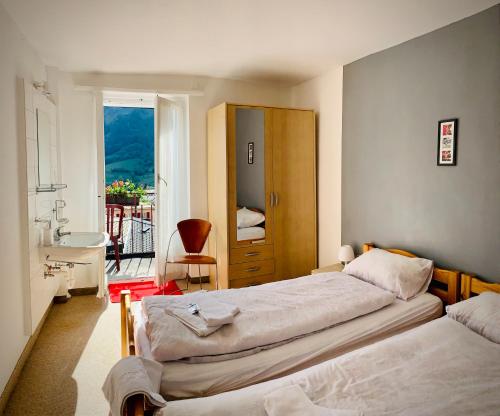a bedroom with two beds and a bathroom with a balcony at Weisses Rössli in Leukerbad