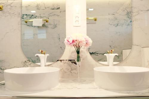 un baño con 2 lavabos y un jarrón de flores rosas en Villa Grand Pinea en Čilipi