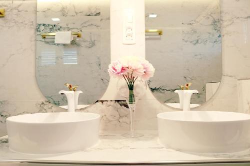 a bathroom with two sinks and a vase of pink flowers at Villa Grand Pinea in Čilipi