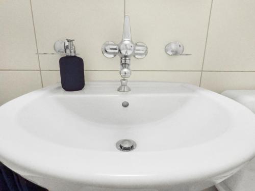 a white bathroom sink with a soap dispenser on it at ARISER - Zug Mountain View Business Apartment in Zug