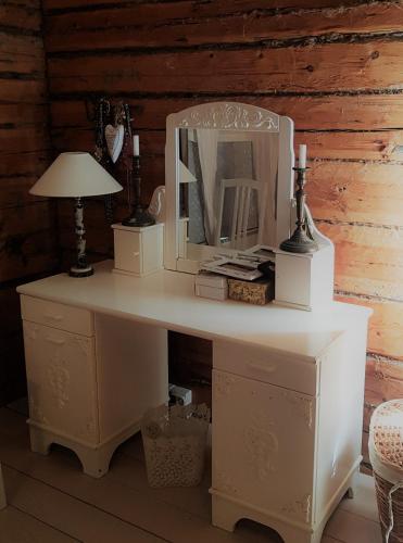 a white desk with a mirror and a lamp at Hirsihuvila, sauna ja kylpyamme, levollista olemista in Loppi