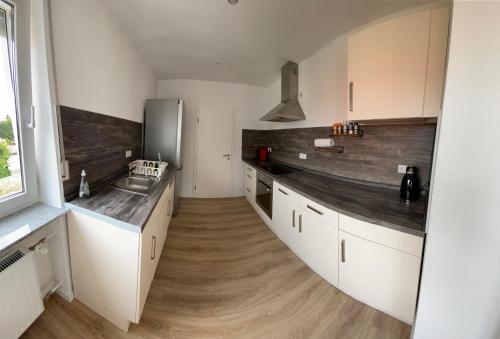 a kitchen with white cabinets and a wooden floor at Moderne Ferienwohnung Hergolshausen in Waigolshausen