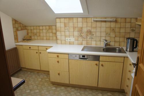una pequeña cocina con armarios de madera y fregadero en Appartements Gärtner en Bichlbach