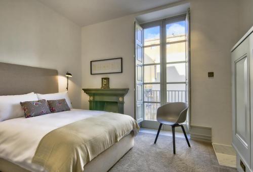 a bedroom with a bed and a chair and a window at 10 Strait Street Apartments in Valletta