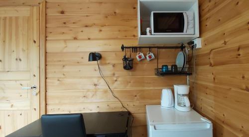 a bathroom with a wooden wall with a refrigerator and a microwave at Hillside Rooms in Ivalo
