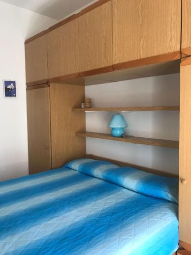 ein Schlafzimmer mit einem Bett mit blauer Bettwäsche und Holzregalen in der Unterkunft Grazioso appartamento a Loano in Loano