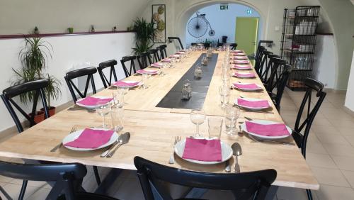 - une longue table avec des serviettes roses et des verres à vin dans l'établissement Hostel les Terrasses du Roc, à Saint-André-de-Roquepertuis