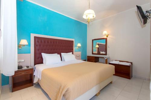 a bedroom with a large bed and a blue wall at Olympic Apartments in Parga