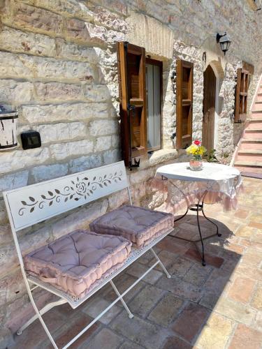 a bench and a table in front of a stone building at B&B Il Poggetto in Serra SantʼAbbondio