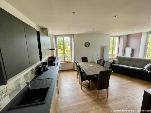 een keuken en een woonkamer met een tafel en een bank bij L'École Buissonnière in Saint-Vigor-le-Grand