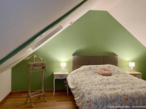 a bedroom with a bed with a green wall at L'École Buissonnière in Saint-Vigor-le-Grand