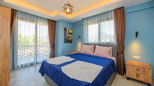 a bedroom with a bed with blue walls and windows at Söğüt 3 - 4 Bedroom with jacuzzi in Fethiye in Fethiye