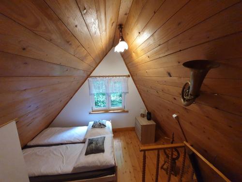Zimmer im Dachgeschoss mit einem Bett in einer Holzdecke in der Unterkunft Leśny Zakątek in Dębica