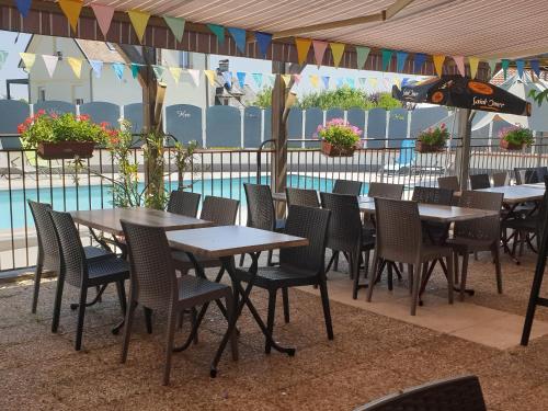 - une rangée de tables et de chaises à côté de la piscine dans l'établissement Logis Hôtel Restaurant Cruzel, à Maurs