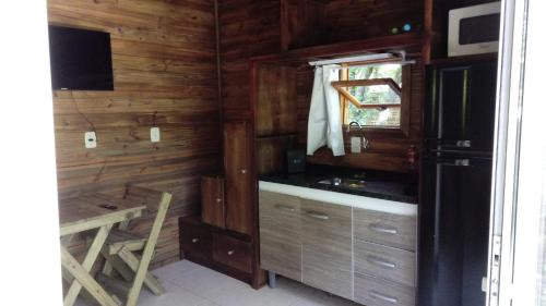 a kitchen with wooden walls and a sink and a window at Tiny House II - Sítio dos Wolff in Gravataí