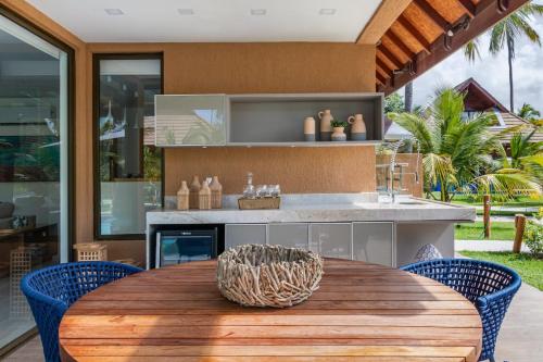 an outdoor kitchen with a wooden table and blue chairs at Warung Praia Dos Carneiros in Praia dos Carneiros