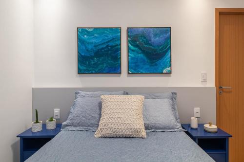 a bedroom with a bed with three paintings on the wall at Warung Praia Dos Carneiros in Praia dos Carneiros