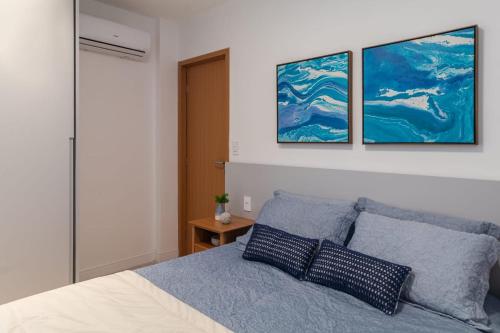 a bedroom with a bed with three paintings on the wall at Warung Praia Dos Carneiros in Praia dos Carneiros